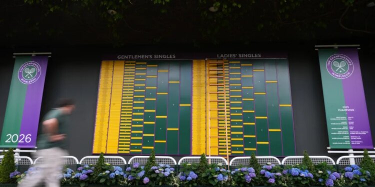 A visitor walks by the Gentlemen's Singles and Ladies' Singles match boards at Wimbledon.