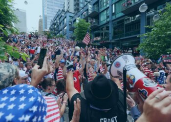 An image collage containing 1 images, Image 1 shows Crowds of fans dressed in red, white, and blue, wave their hands in the air and cheer for the US soccer team in Seattle