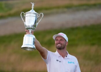 Wyndham Clark holding the U.S. Open golf tournament trophy.