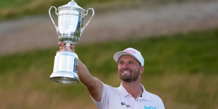 Wyndham Clark holding the U.S. Open golf tournament trophy.
