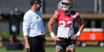 Klay Kubiak smiles at Christian McCaffrey during a practice session.