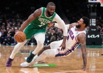 Boston Celtics guard Jaylen Brown drives to the basket against Philadelphia 76ers forward Paul George, who is falling backward.
