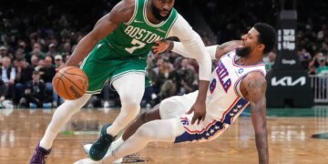 Boston Celtics guard Jaylen Brown drives to the basket against Philadelphia 76ers forward Paul George, who is falling backward.
