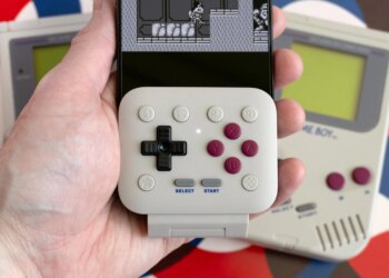 The 8BitDo FlipPad attached to an iPhone held in a person’s hand with a Game Boy game on screen.