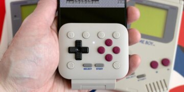 The 8BitDo FlipPad attached to an iPhone held in a person’s hand with a Game Boy game on screen.