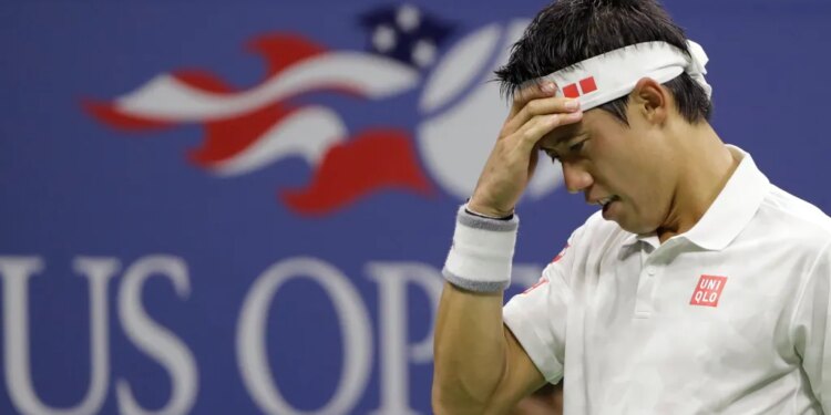Kei Nishikori holding his head in his hand during a tennis match.
