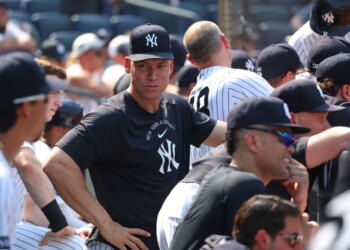 Aaron Judge in the dugout wearing a black Yankees cap and shirt.