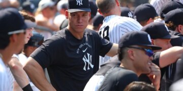 Aaron Judge in the dugout wearing a black Yankees cap and shirt.