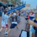 Two men fighting with a blue table over their heads in a crowd of people.