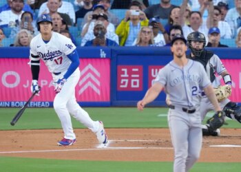 Los Angeles Dodgers' Shohei Ohtani heads to first base as Colorado Rockies pitcher Michael Lorenzen and catcher Braxton Fulford watch.