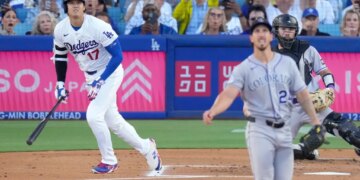 Los Angeles Dodgers' Shohei Ohtani heads to first base as Colorado Rockies pitcher Michael Lorenzen and catcher Braxton Fulford watch.