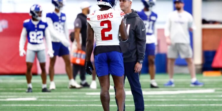 New York Giants cornerback Deonte Banks talking to head coach John Harbaugh during football practice.