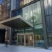 A modern building entrance with a prominent canopy over glass doors and the address 125 above the doors.