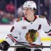 Connor Bedard in a white Blackhawks jersey during an NHL game.