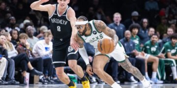 Gary Trent Jr. driving down court with Danny Wolf giving chase during a basketball game.
