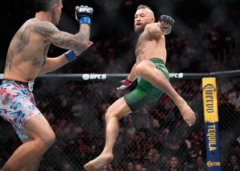 Conor McGregor attempts a flying kick on Max Holloway during their UFC fight.