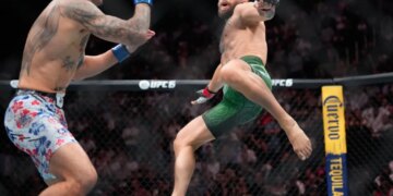 Conor McGregor attempts a flying kick on Max Holloway during their UFC fight.