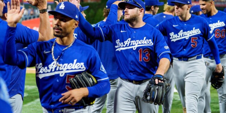 The Los Angeles Dodgers baseball team, including Max Muncy (13), Mookie Betts, and Freddie Freeman (5), high-fiving.