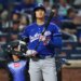 Shohei Ohtani at bat, wearing a blue Dodgers jersey and helmet, holding a bat, with a catcher behind him.
