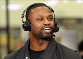 Former NFL player Bart Scott speaking into a microphone while wearing headphones.