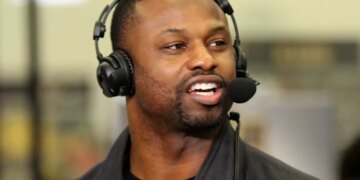 Former NFL player Bart Scott speaking into a microphone while wearing headphones.