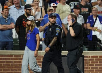 A fan is escorted off the field by police and security after entering the field during the ninth inning a baseball game between the Baltimore Orioles and the Chicago Cubs, Wednesday, July 8, 2026, in Baltimore.