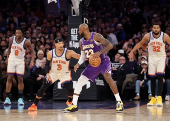 LeBron James of the Lakers dribbles the ball while being defended by Josh Hart of the Knicks.