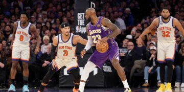 LeBron James of the Lakers dribbles the ball while being defended by Josh Hart of the Knicks.