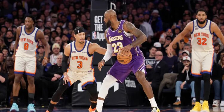 LeBron James of the Lakers dribbles the ball while being defended by Josh Hart of the Knicks.