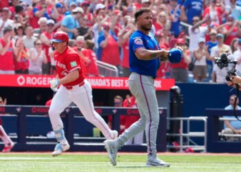 Toronto Blue Jays player Sean Keys runs the bases while New York Mets pitcher Freddy Peralta reacts in a baseball game.