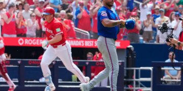 Toronto Blue Jays player Sean Keys runs the bases while New York Mets pitcher Freddy Peralta reacts in a baseball game.