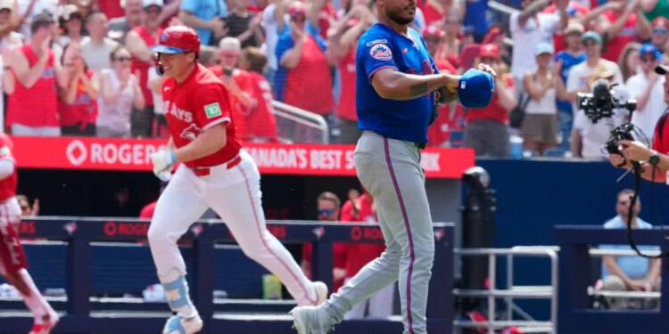 Toronto Blue Jays player Sean Keys runs the bases while New York Mets pitcher Freddy Peralta reacts in a baseball game.
