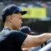 New York Yankees player Kyle Higashioka wearing a baseball cap and sunglasses looks to the right from the dugout.