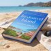Treasured Island by Michael Gross, on a beach with the ocean and hills in the background.