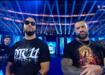 Two men in t-shirts posing at a wrestling event.