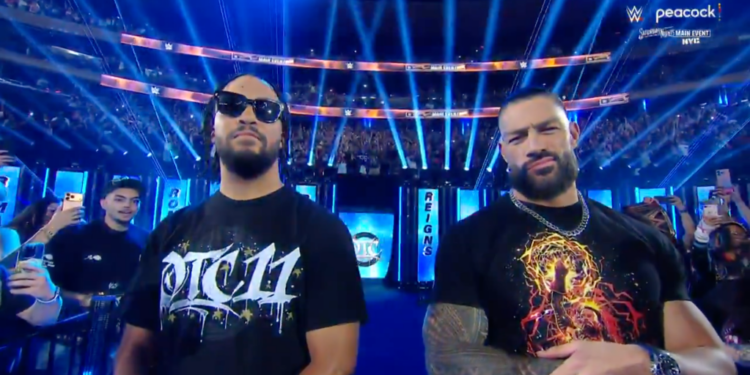 Two men in t-shirts posing at a wrestling event.