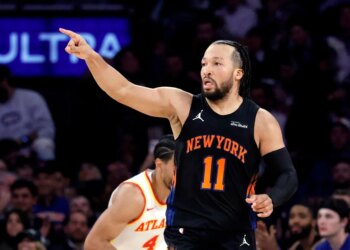 New York Knicks guard Jalen Brunson points while running during an NBA playoff game.