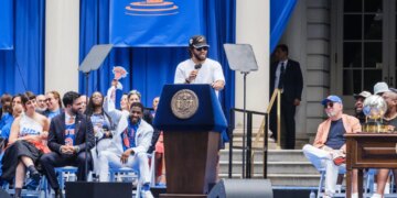 Knicks player Jalen Brunson speaks at a podium to celebrate the team's key to the city ceremony at City Hall.