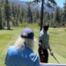A man with long blonde hair and a blue hat from behind on a golf course.