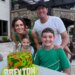 Family of four posing with a birthday cake that reads "BREXTON" in front of a building with a stone archway.