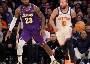 LeBron James defending Jalen Brunson as Brunson dribbles the basketball downcourt during a Lakers vs. Knicks game.
