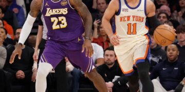 LeBron James defending Jalen Brunson as Brunson dribbles the basketball downcourt during a Lakers vs. Knicks game.