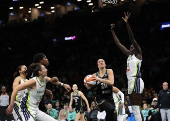 Sabrina Ionescu drives past Dallas Wings defenders during a WNBA game.