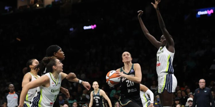 Sabrina Ionescu drives past Dallas Wings defenders during a WNBA game.