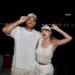 Travis Kelce and Taylor Swift wearing "Captain" and "First Mate" hats, respectively, with their arms around each other.