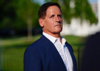 Mark Cuban, a white man with dark hair, wears a blue suit jacket and white shirt, looking forward and slightly to the right.