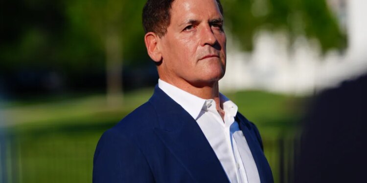 Mark Cuban, a white man with dark hair, wears a blue suit jacket and white shirt, looking forward and slightly to the right.