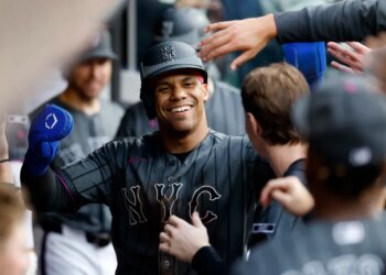 New York Mets left fielder Juan Soto (22) smiling in the dugout after scoring on a SAC fly by New York Mets shortstop Bo Bichette (19).