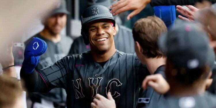 New York Mets left fielder Juan Soto (22) smiling in the dugout after scoring on a SAC fly by New York Mets shortstop Bo Bichette (19).