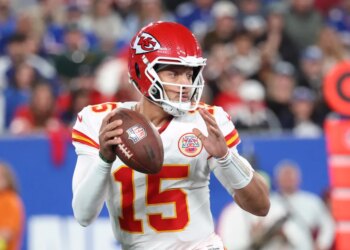 Patrick Mahomes #15 of the Kansas City Chiefs in a white jersey and red helmet with a football in hand.